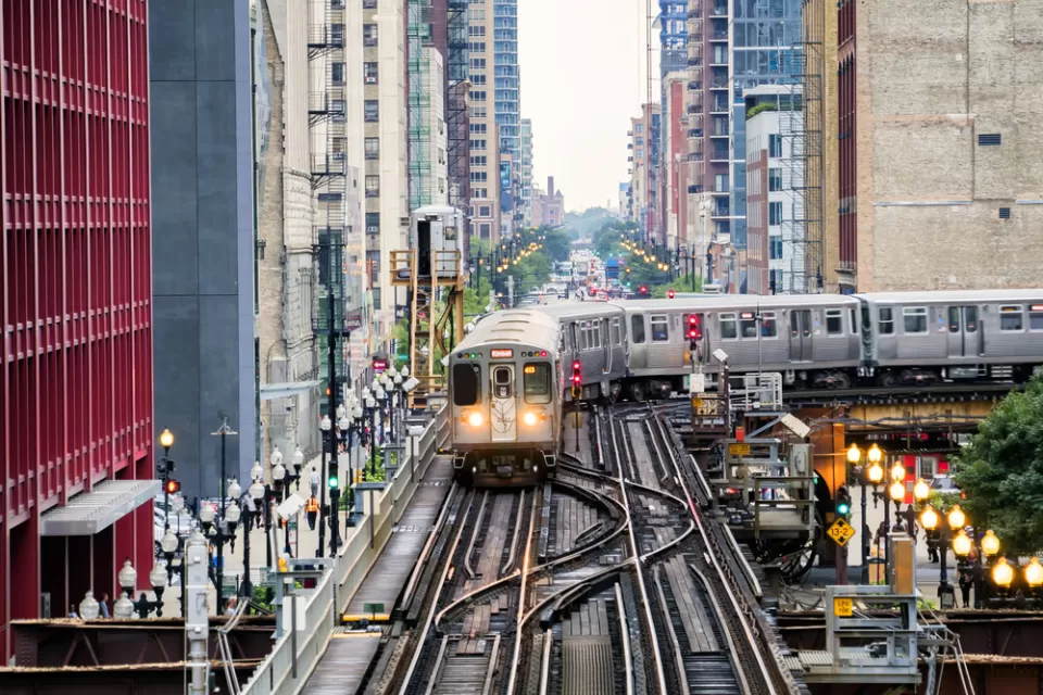 Chicago elevated train over busy city street surrounded by high-rise buildings